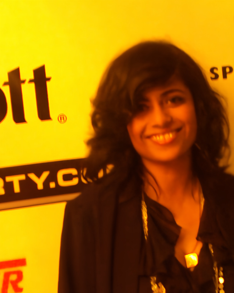 Night portrait, after: the same woman and yellow backdrop, with less speckle in the hair and jacket